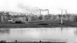 Black and white view from Moncrieff Island showing the North Inch, with smoking industrial chimney stacks behind.