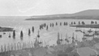 Black and white view over rooftops of Stromness across to fishing fleet returning to harbour.