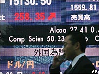 A Japanese man passing a board showing share prices