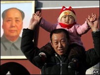 Chinês posa para foto com filho em frente à foto do líder comunista Mao Zedong