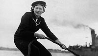 A member of the WRNS makes fast the motor boat she has been using to ferry mail and goods to ships at anchor