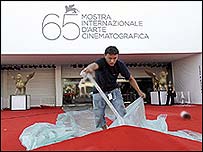 A worker prepares the red carpet at the entrance of the cinema palace